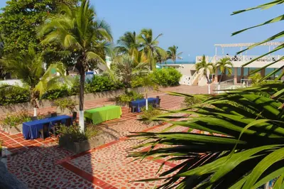 a courtyard with blue benches and palm trees at Hotel Dorado Plaza Punta Arena in Tierra Bomba