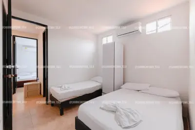 a bedroom with two beds and a mirror at Caribbean Town Tolu in Tolú