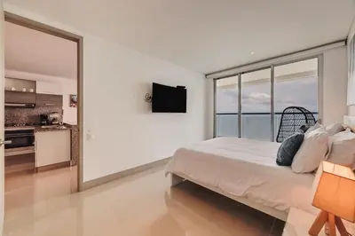 a white bedroom with a bed and a large window at Palmetto Beach by MOME in Cartagena de Indias