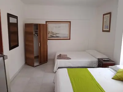 a hotel room with two beds and a refrigerator at Habitación I frente a la playa ( Bocagrande ) in Cartagena de Indias