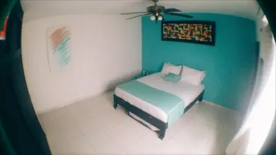 a bedroom with a bed and a blue wall at QuillaHost Tropical Apartment in Barranquilla