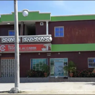 a red and green building with a clock on it at Hotel Troncal Del Caribe in Ciénaga
