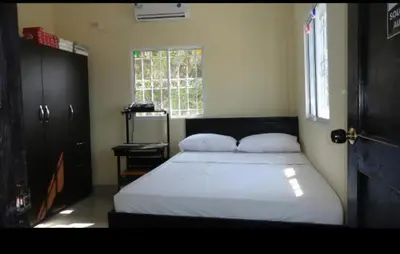 a bedroom with a bed with white sheets and a window at Hotel Troncal Del Caribe in Ciénaga