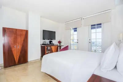 a white bedroom with a bed and a tv at NH Royal Urban Cartagena in Cartagena de Indias