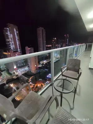 a balcony with chairs and a city skyline at night at luxuriuso apartament in Cartagena de Indias