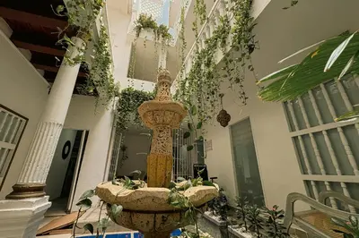 a fountain in the middle of a building with plants at Hotel AT THE PARK in Cartagena de Indias