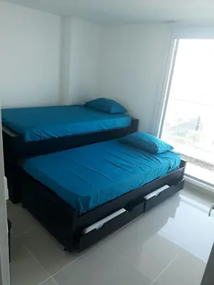 a bed with blue sheets in a room with a window at Apartamento seaway 935 Morros, La Boquilla in Cartagena de Indias