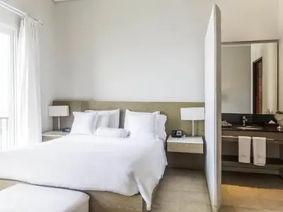 a bedroom with a large white bed and a bathroom at Hotel Boutique Bovedas de Santa Clara By Accor in Cartagena de Indias