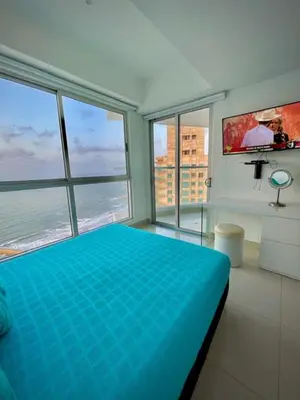 a bedroom with a blue bed in a room with windows at Beach front Apartament in Cartagena de Indias