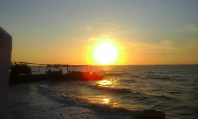 a sunset over the ocean with a boat in the water at Cabaña Coveñas Punta Bolivar in Coveñas