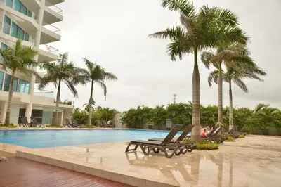 a woman sitting in lounge chairs next to a swimming pool at Modern 3 Bedroom Apartment with sea-beach view in Cartagena de Indias