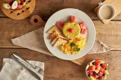 a plate of breakfast food with eggs and crackers and fruit at Genesis Hotel in Sincelejo