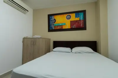 a bedroom with a white bed and a painting on the wall at Genesis Hotel in Sincelejo