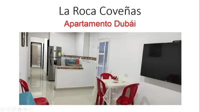 a kitchen with a table with red chairs and a tv at La Roca Coveñas Apartamentos in Coveñas