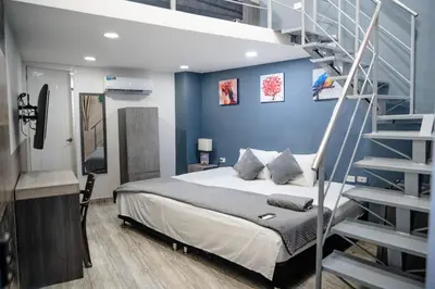 a bedroom with a bed and a spiral staircase at Bahia 79 Apartasuites Cerca al Centro in Cartagena de Indias