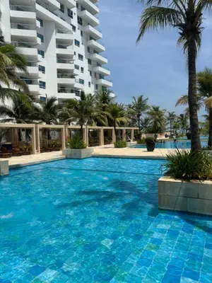 a swimming pool with palm trees and a building at Apartamento Cartagena Morros Epic 25 in Cartagena de Indias