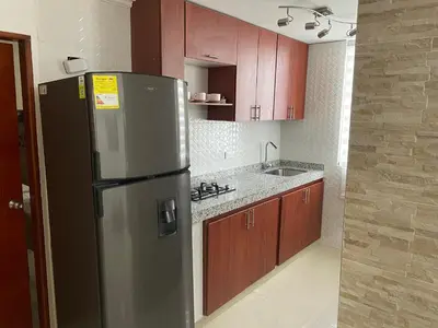 a kitchen with a stainless steel refrigerator and wooden cabinets at Alojamientos Cartagena Edificio Los Delfines in Cartagena de Indias