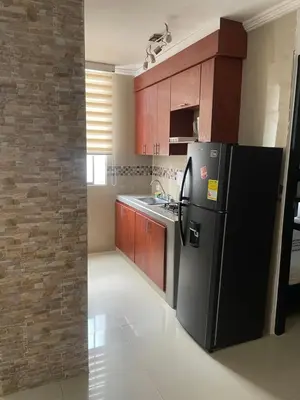 a kitchen with a black refrigerator and wooden cabinets at Alojamientos Cartagena Edificio Los Delfines in Cartagena de Indias