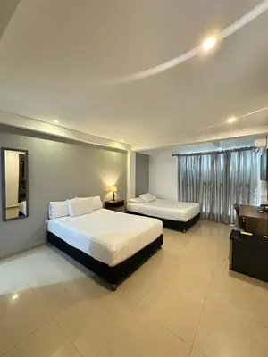 a hotel room with two beds and a desk at Hotel Amoek in Cartagena de Indias