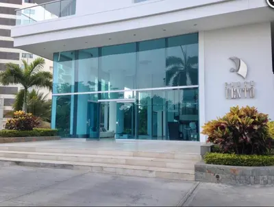 a large glass building with palm trees in front of it at Cartagena Beach Front Apartments in Cartagena de Indias