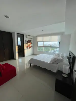 a white bedroom with a large bed and a red couch at Cartagena Beach Front Apartments in Cartagena de Indias
