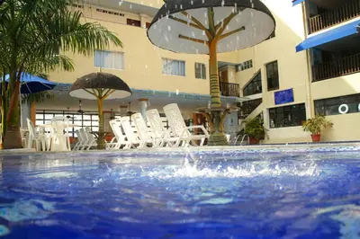 a pool with chairs and umbrellas in front of a hotel at Hotel Genova Centro in Barranquilla