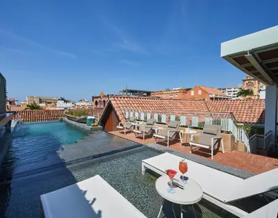 a swimming pool with chairs and tables on a building at Hotel Boutique Casona del Colegio in Cartagena de Indias