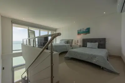 a bedroom with two beds and a staircase with a window at MURANO ELITE NEW OCEAN FRONT DUPLEx in Cartagena de Indias