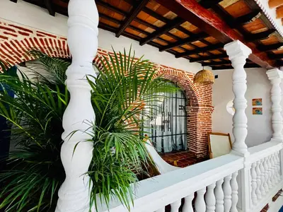 a porch with a white railing and plants at Los Patios Hostel Cartagena in Cartagena de Indias