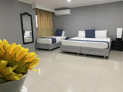 a bedroom with two beds and a vase of yellow flowers at Hotel Puerta de Oro in Barranquilla