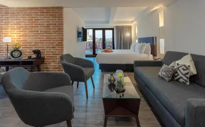 a hotel room with a bed and a couch and chairs at Hotel Santa Catalina By OxoHotel in Cartagena de Indias