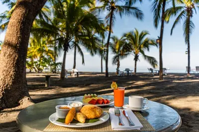 a table with two plates of food and drinks on the beach at Hotel Irotama XXI in Santa Marta