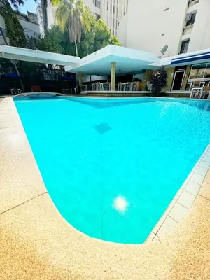 a large blue swimming pool in front of a building at Vallclaire Suites in Barranquilla