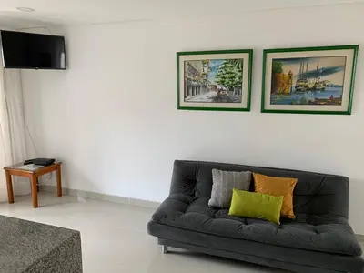 a black couch in a living room with two pictures on the wall at Portofino Cartagena Bocagrande By ICDI in Cartagena de Indias