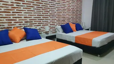 two beds in a room with a brick wall at Casa Evelyn in Cartagena de Indias