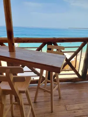 a wooden table and chairs on a deck with the beach at Hotel Calamari Baru in Playa Blanca