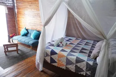 a bedroom with a canopy bed and a blue couch at Hotel Calamari Baru in Playa Blanca
