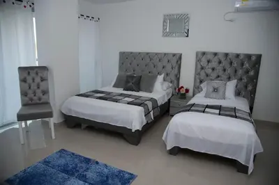 a bedroom with two beds and a chair at Hotel Platinum Barranquilla in Barranquilla