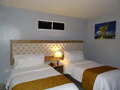 a hotel room with two beds and a lamp at Hotel Prado Real in Barranquilla