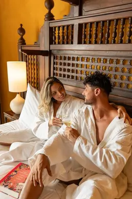 a man and a woman sitting in a bed at Casa Carolina Luxury Wellness Hotel in Cartagena de Indias