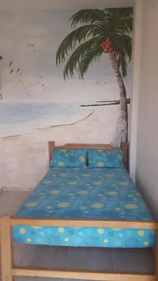 a bed in a room with a painting of a palm tree at Hotel Brisas del Mar San Antero in San Antero