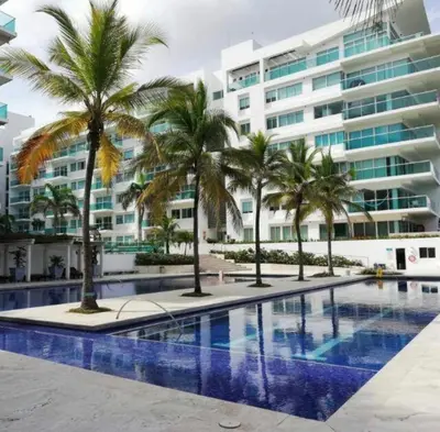 a swimming pool with palm trees in front of a building at APTO EN LA BOQUILLA CARTAGENA MORROS 922 in Cartagena de Indias