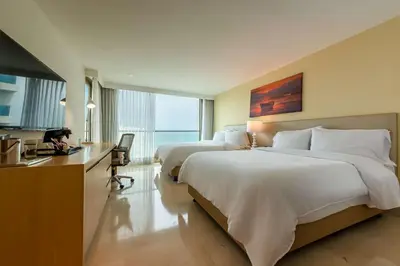a hotel room with two beds and a desk and a kitchen at Radisson Cartagena Ocean Pavillion Hotel in Cartagena de Indias