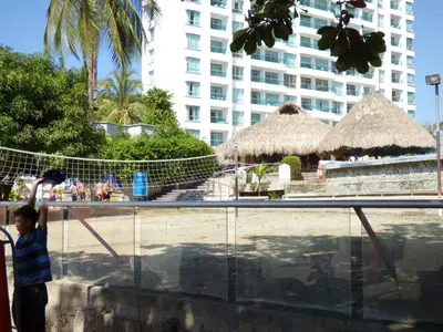 a young boy is looking through a fence at a resort at Costa Azul Suites 403 in Santa Marta