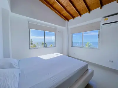 a white bedroom with two windows and a bed at Condominio bahia blanca in Coveñas