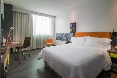 a hotel room with a large bed and a desk at Hampton by Hilton Barranquilla in Barranquilla