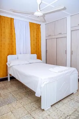 a white bed in a room with orange curtains at Aqui me quedo in Cartagena de Indias