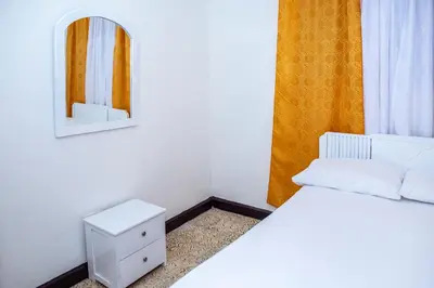 a bedroom with a white bed and a mirror at Aqui me quedo in Cartagena de Indias