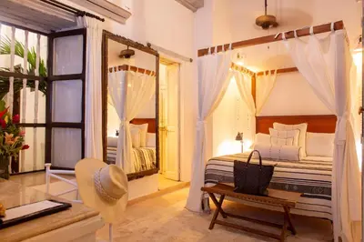 a bedroom with a bed and a table and a mirror at Leones de Alba Hotel Boutique in Cartagena de Indias
