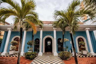 a blue building with palm trees in front of it at Casa Bustamante Hotel Boutique in Cartagena de Indias